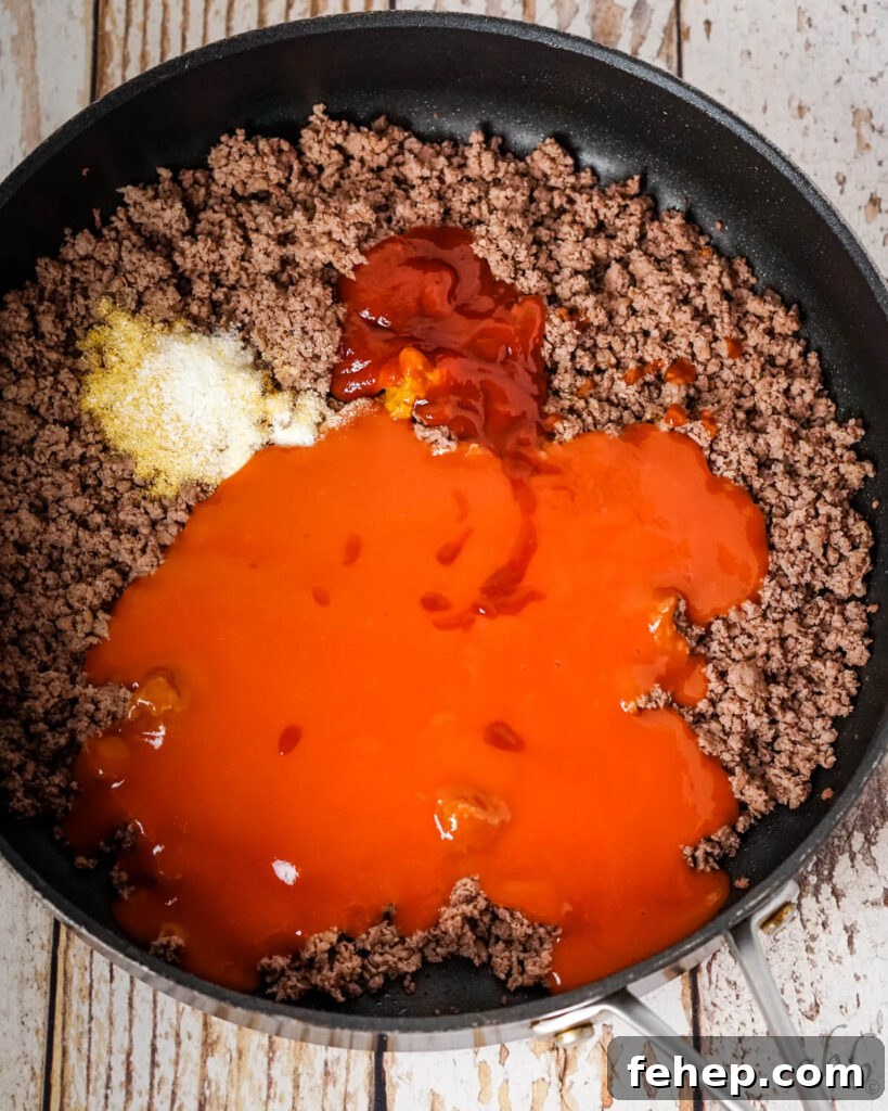 Garlic Bread Sloppy Joes: Cheesy, Savory Sloppy Joe Twist 6 Tomato soup, Worcestershire sauce, yellow mustard, and ketchup, onion powder, salt, and garlic powder, and browned ground beef sitting in a medium black skillet.
