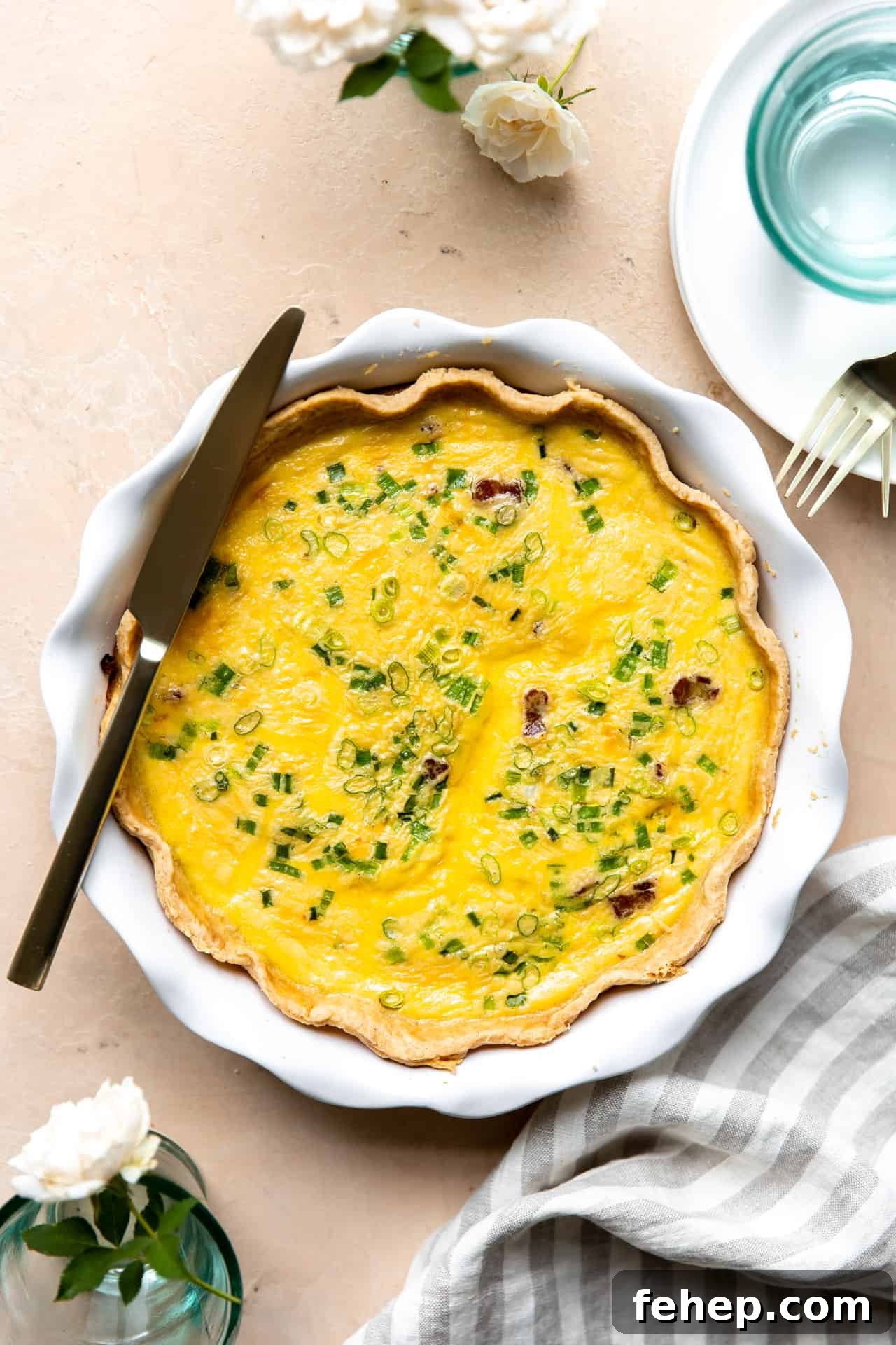 Classic French Quiche Recipe: Flaky Crust and Creamy Filling 10 Baked Quiche in a white pie dish with a knife laid on top for serving.
