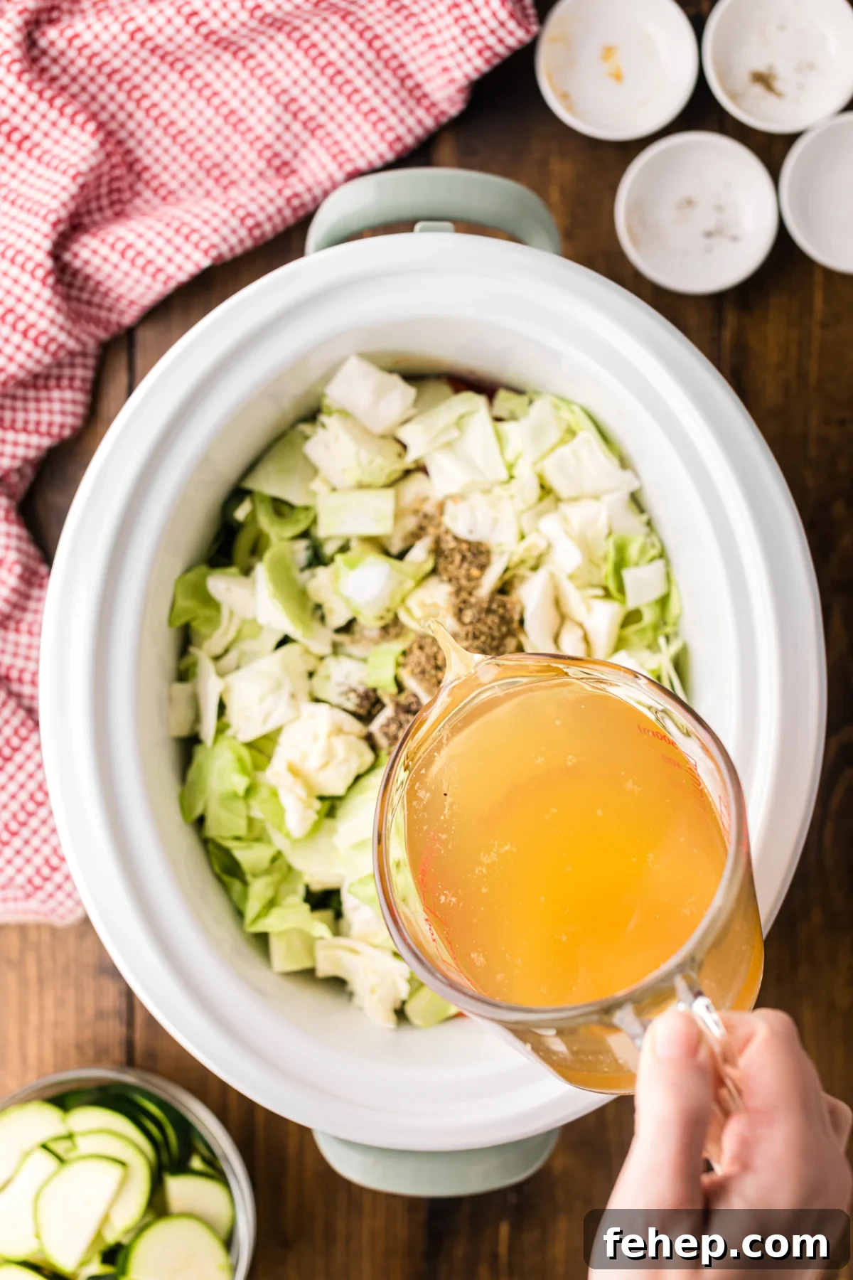 Pouring chicken broth into a crockpot.
