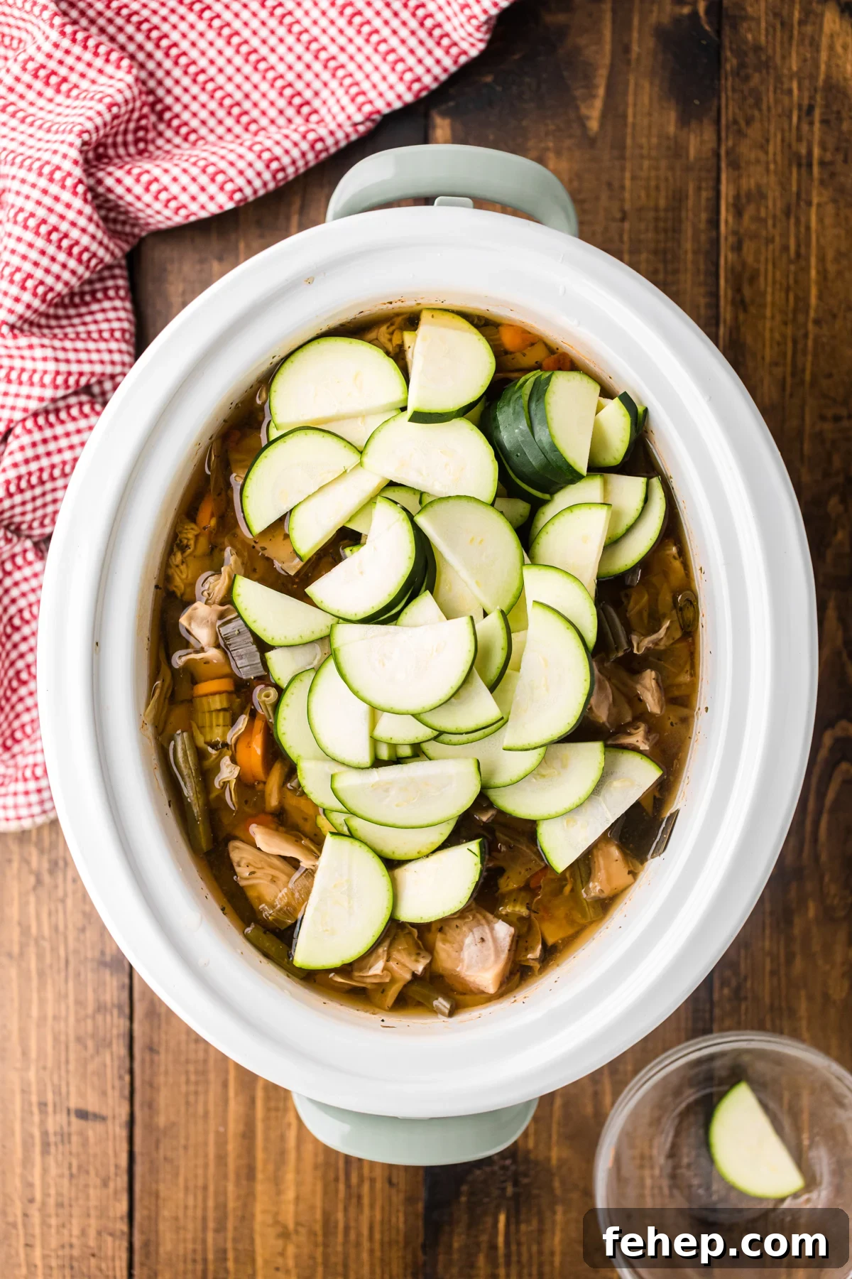 Zucchini added to cooked soup in a crockpot.