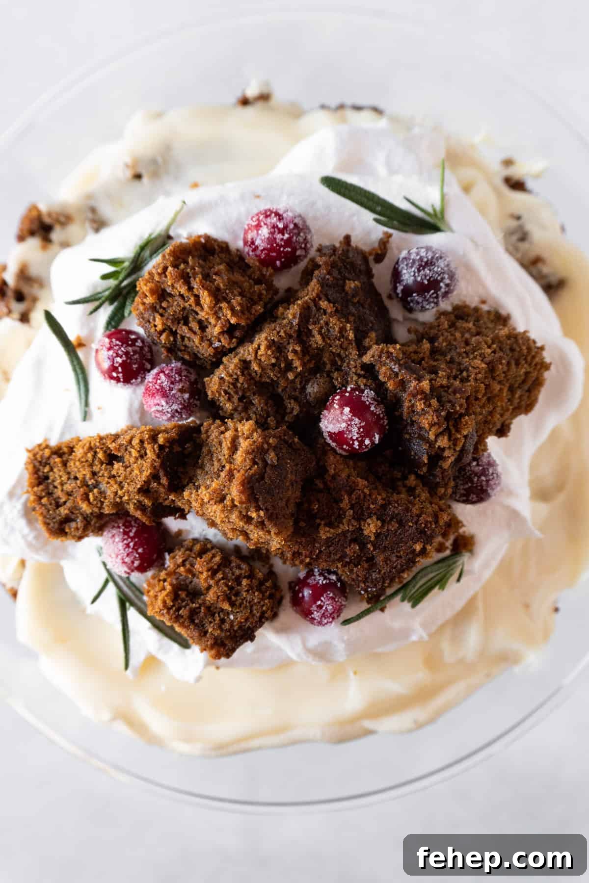 Gingerbread Trifle Recipe: Festive Layered Dessert for Holidays 5 Top of gingerbread trifle showing garnish of candied cranberries, rosemary, and gingerbread cake cubes.