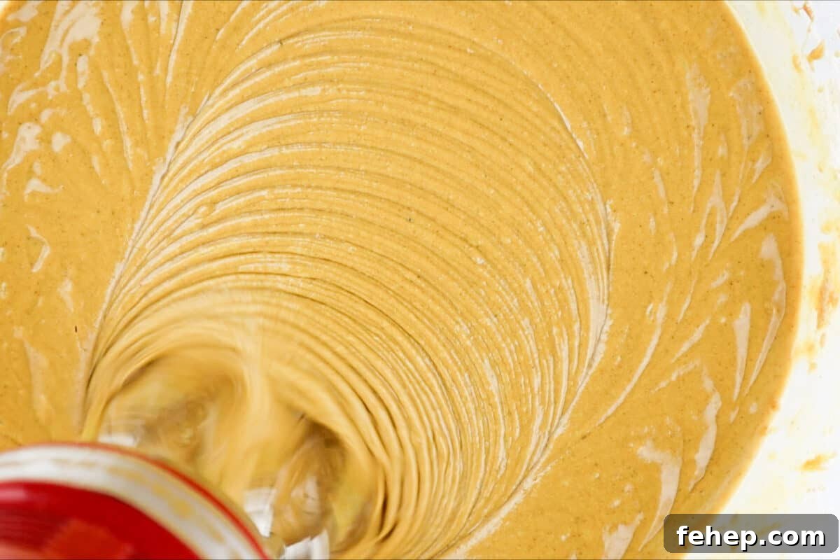 Gingerbread Trifle Recipe: Festive Layered Dessert for Holidays 9 gingerbread cake batter mixed in bowl with hand mixer.