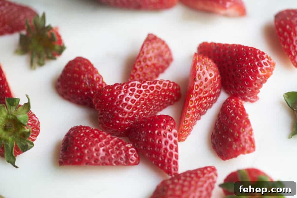 Creamy Dairy-Free Strawberry Milkshake Recipe 3 Fresh strawberry slices on a marble cutting board.