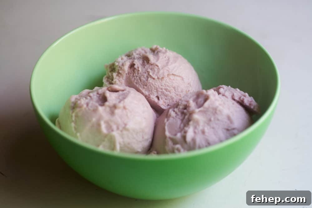 Creamy Dairy-Free Strawberry Milkshake Recipe 5 A bowl of dairy-free strawberry frozen dessert in a green plastic bowl.