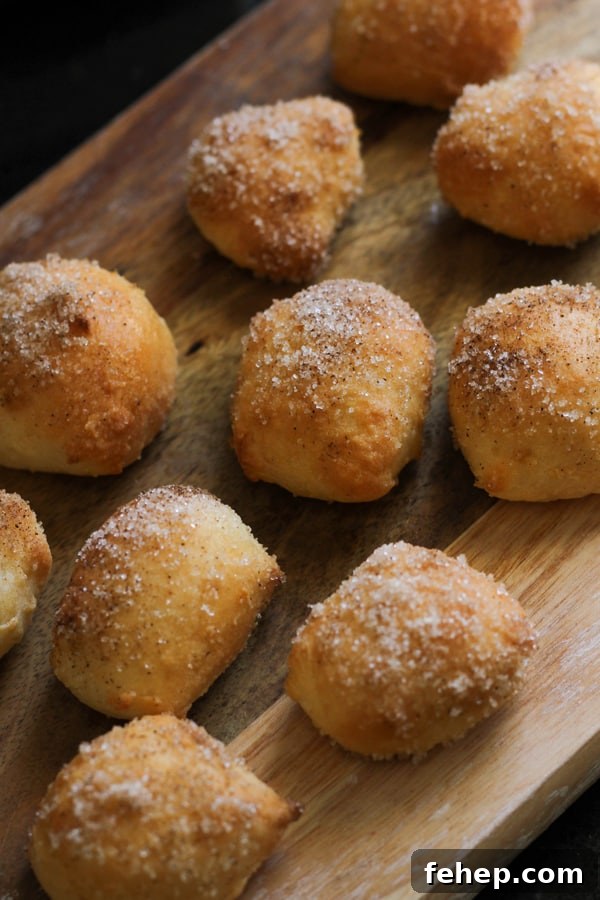 Cinnamon Sugar Pretzel Bites (Yeast-Free) 2 pretzel bites covered in cinnamon sugar on a wooden board.