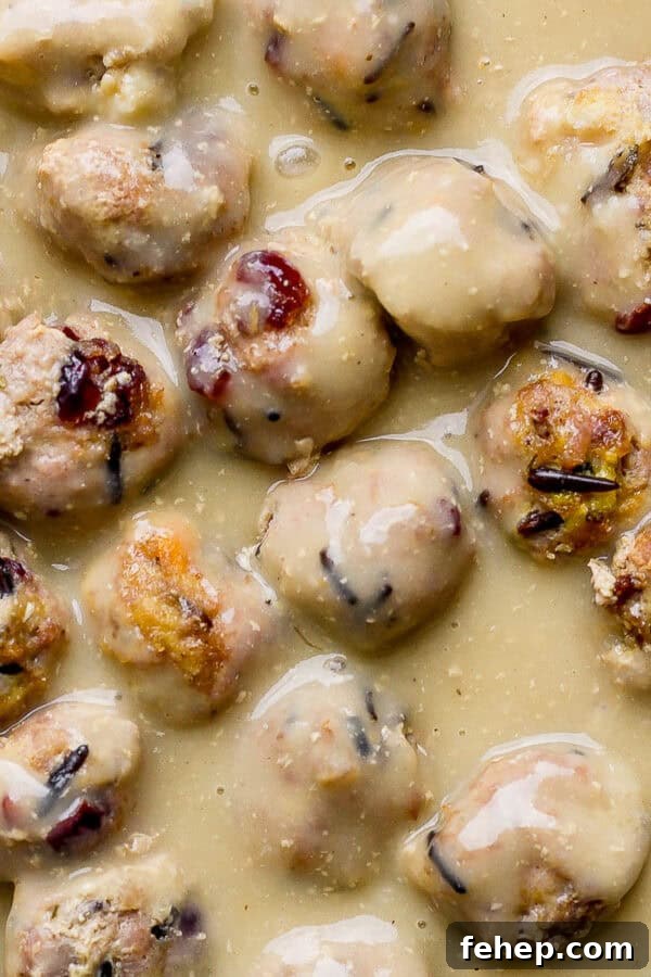 Skillet with cranberry wild rice meatballs in gravy.