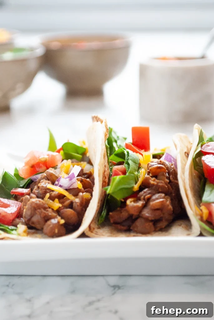 a plate of 3 instant pot lentil tacos with bowls in the background.
