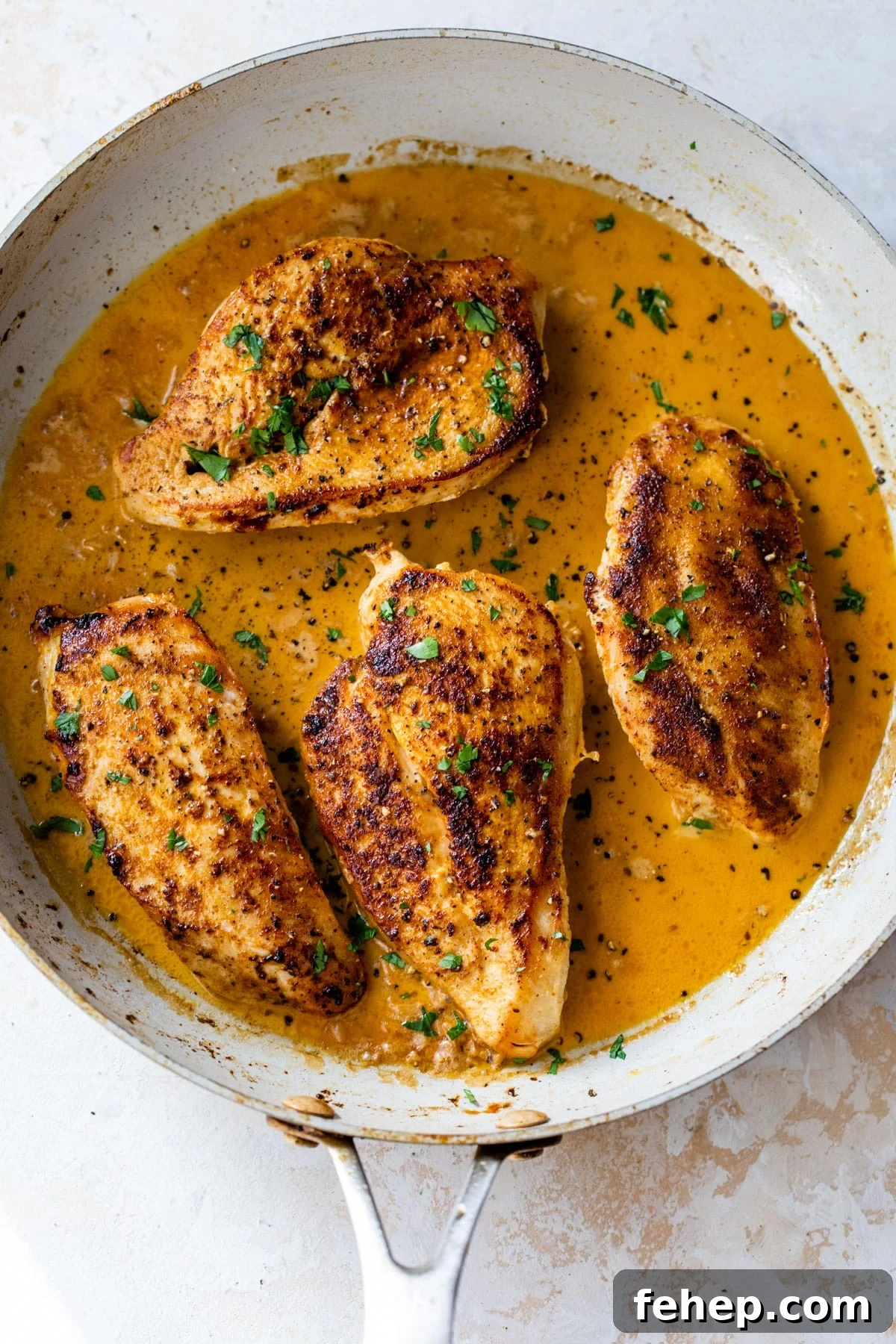 four pieces of cajun chicken in a large skillet with chopped parsley on top