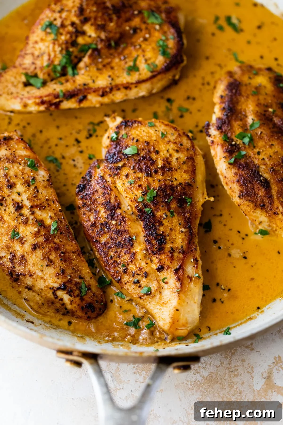close-up of cajun chicken in a large skillet with chopped parsley on top