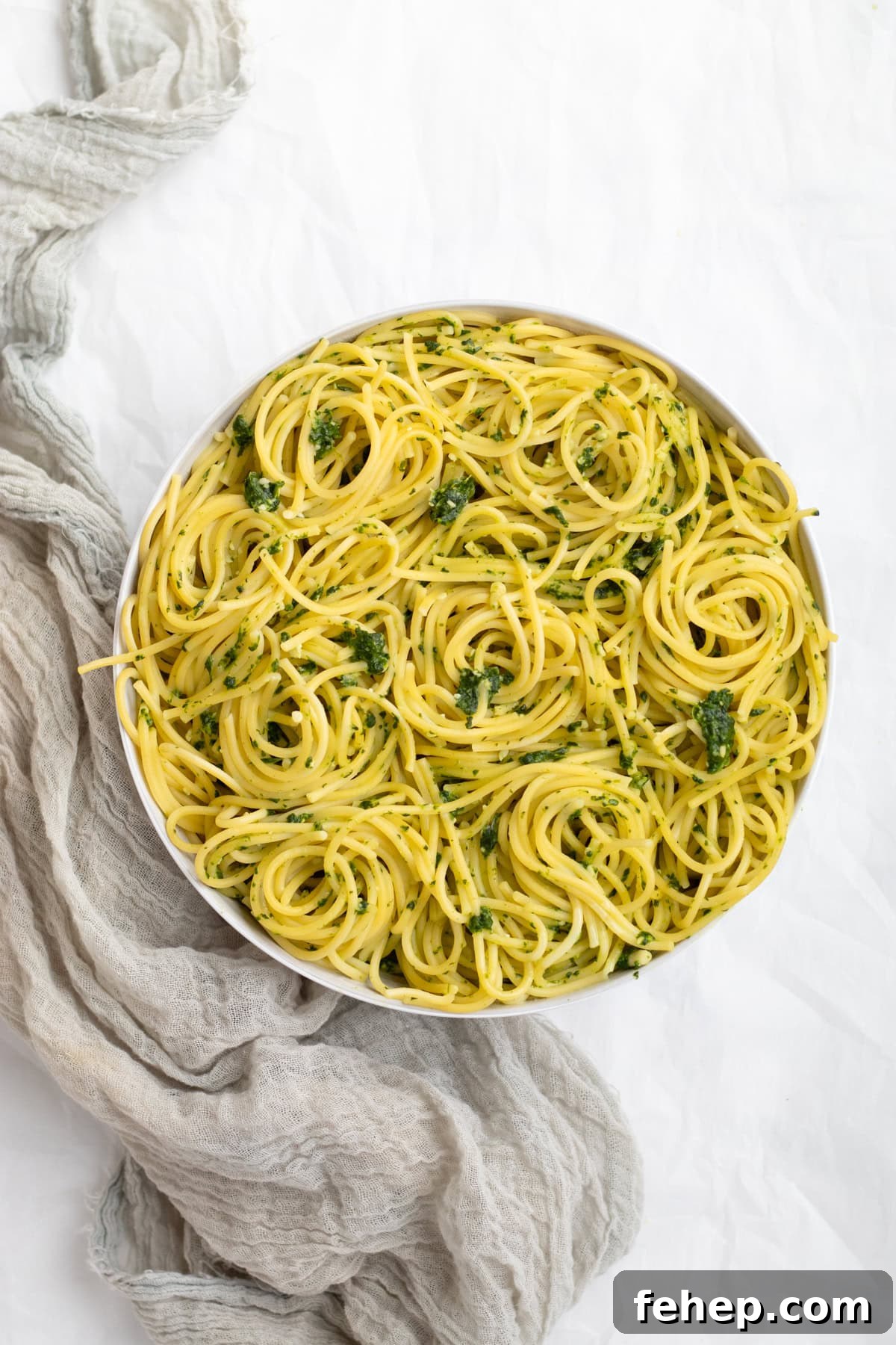 spinach pesto pasta swirled in a white serving bowl