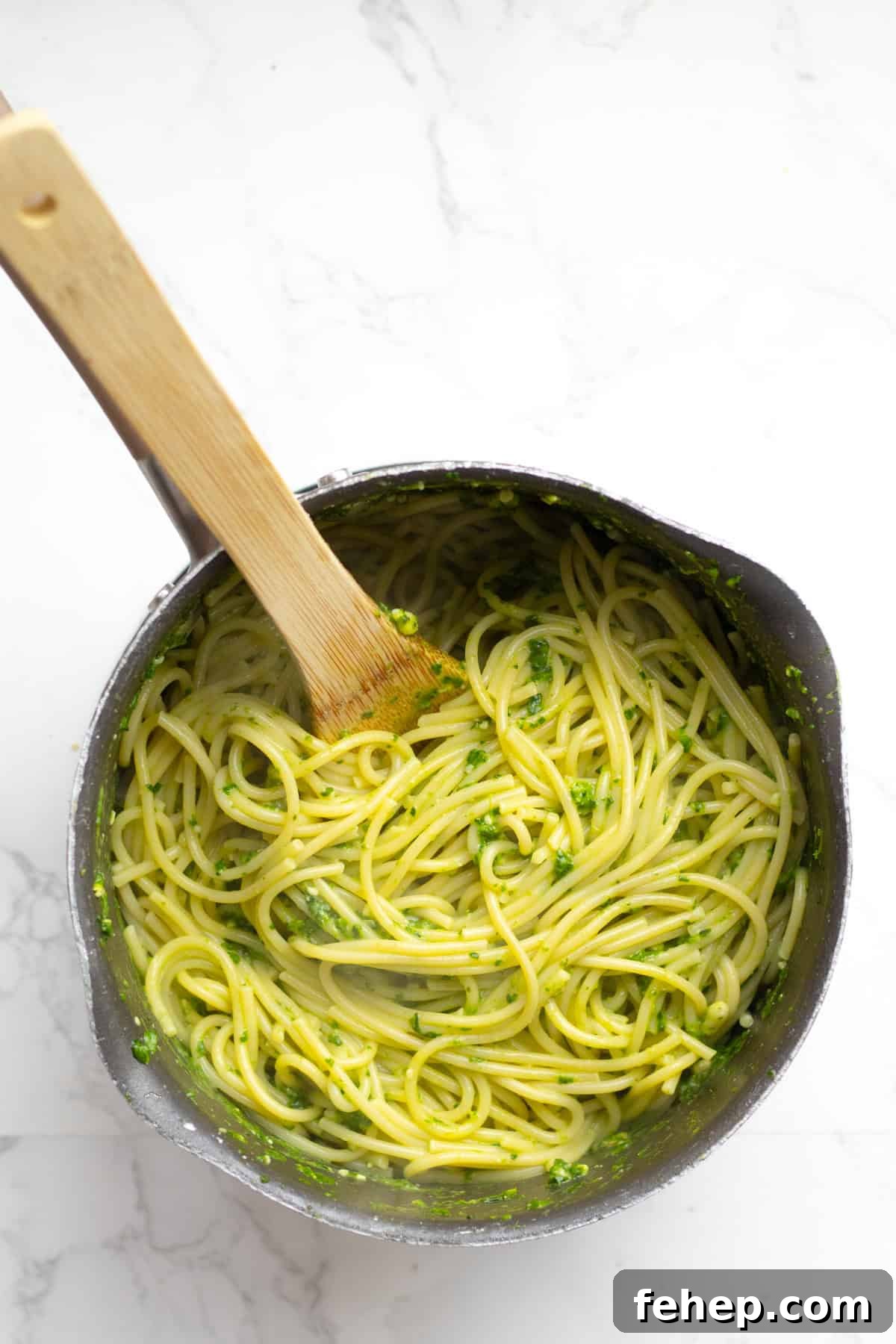 pesto and pasta being mixed in a pot