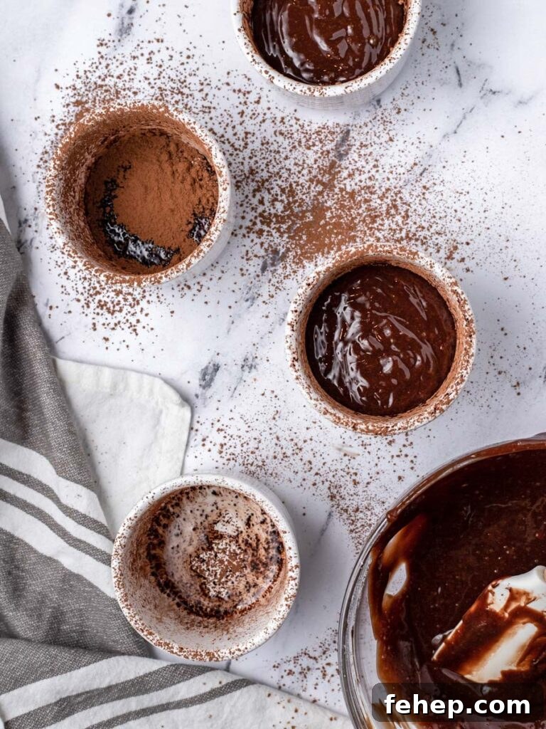 Multiple ramekins dusted with powder and 2 filled with batter.
