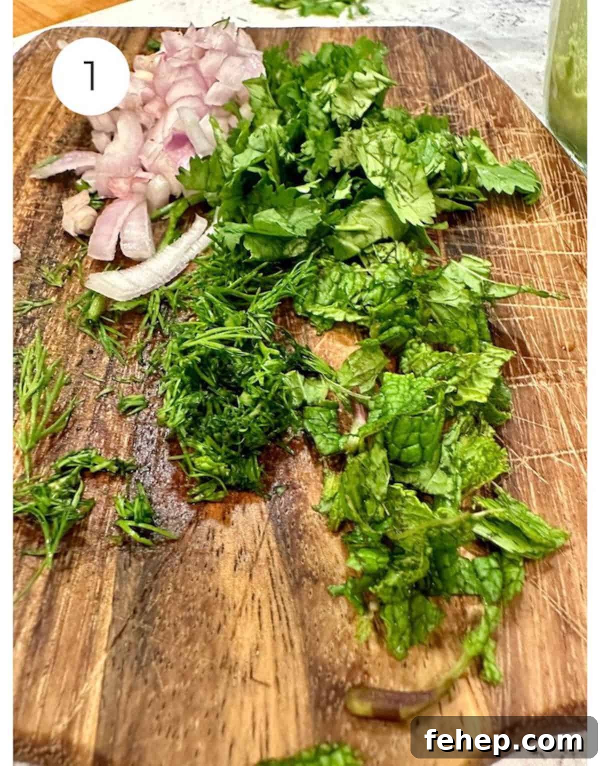 Chopped herbs and onion on a cutting board.