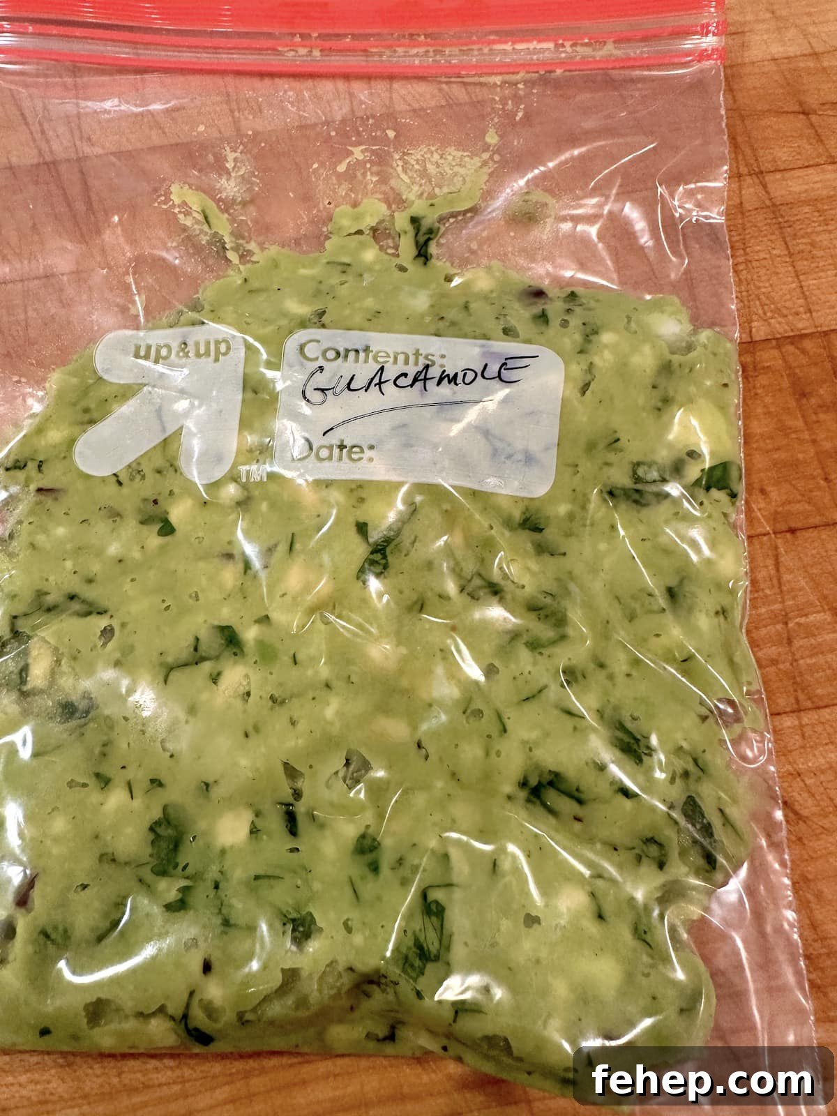 Guacamole in a storage bag on a cutting board.