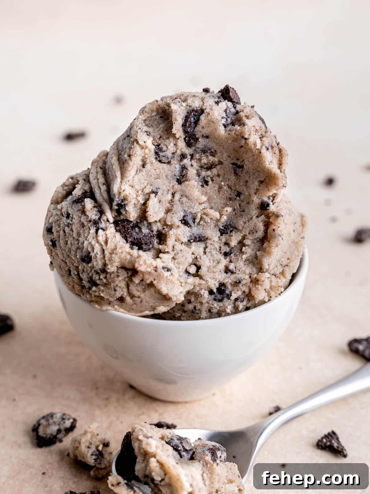Edible Cookies and Cream Cookie Dough Recipe for Safe Snacking 5 Scoops of edible Oreo cookie dough in a small bowl with a spoonful taken out.
