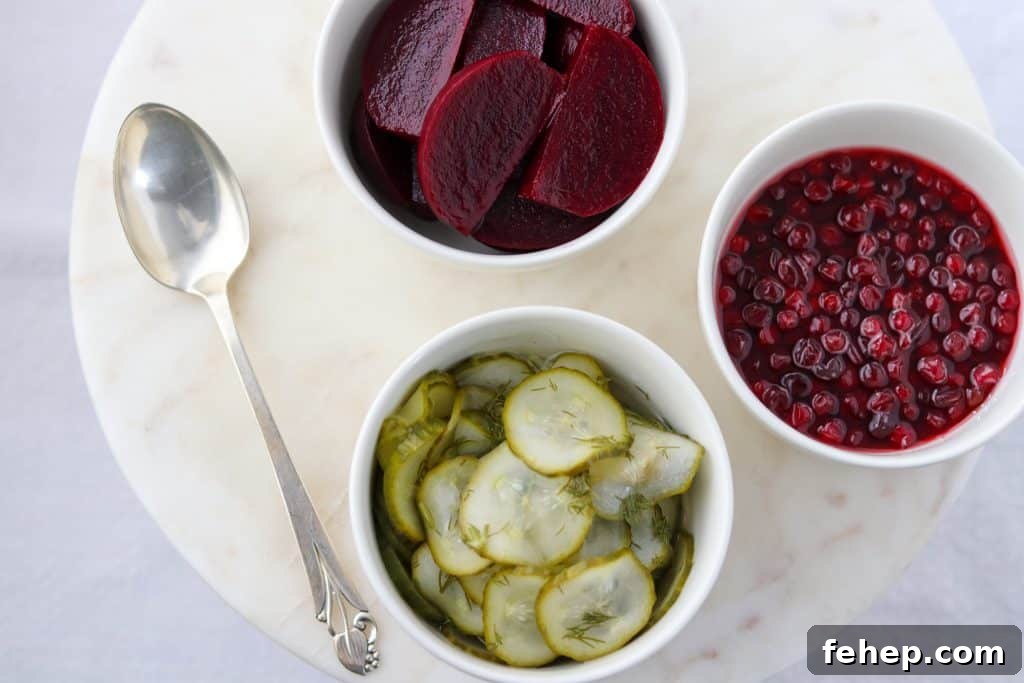 Modern Scandinavian Christmas Eve Smorgasbord Menu Ideas 4 Bowls of roasted beets, pickles and lingonberries with a spoon on a marble surface
