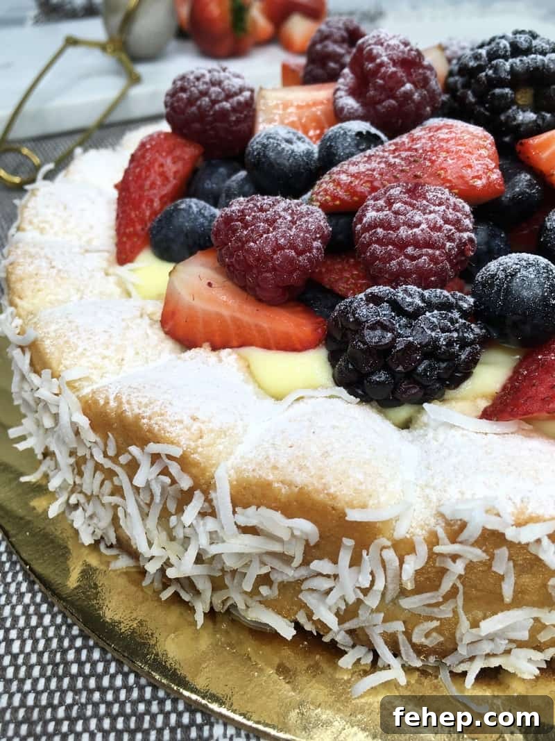 15 Irresistible Cake Recipes for Every Occasion 7 Coconut dacquoise cake topped with red fruit and sprinkled with icing sugar on a cake platter