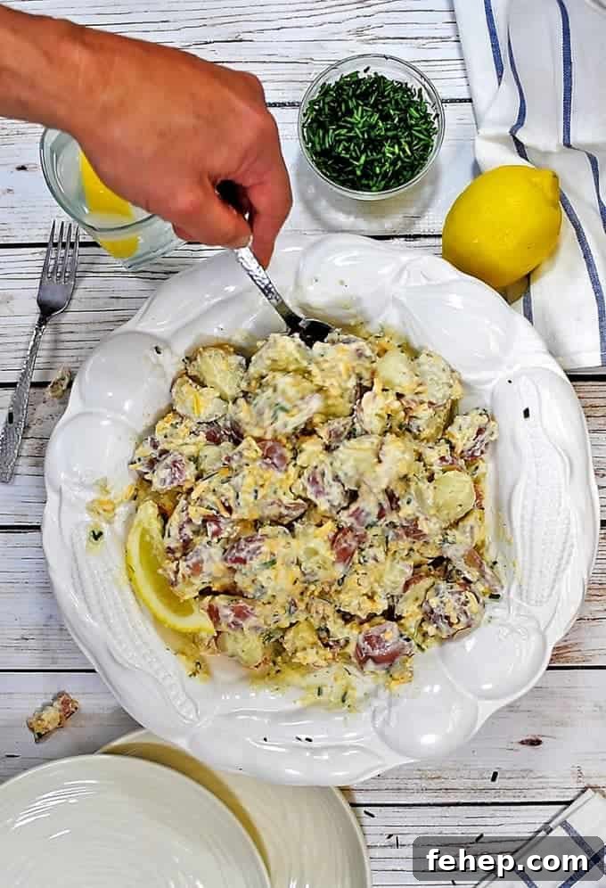 Creamy Bacon Ranch Potato Salad Recipe for Summer BBQs 3 A person holding a plate of food with a knife, with potato salad
