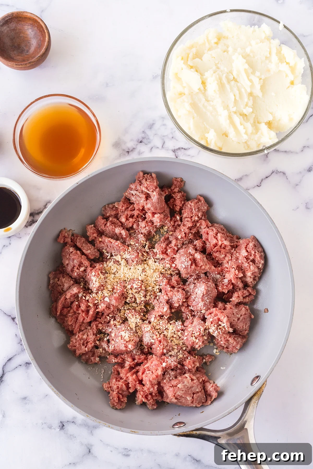 Ground beef in skillet with minced onion ready to brown.