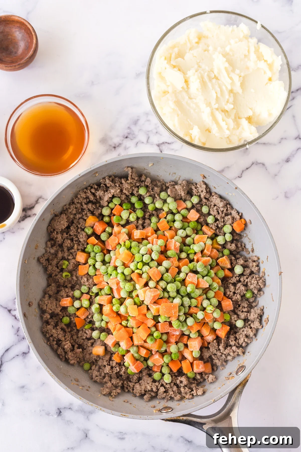 Frozen peas and carrots added to  browned ground beef in skillet.