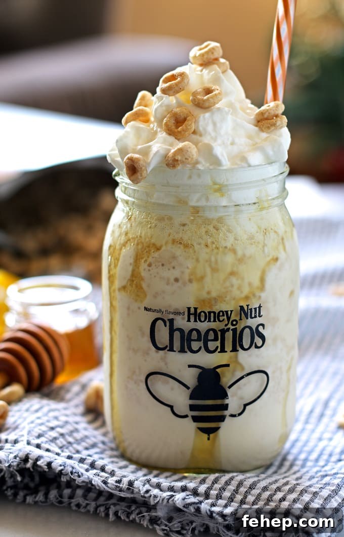 honey nut Cheerios mug filled with cereal milkshake topped with whipped cream, Honey Nut Cheerios. orange striped straw