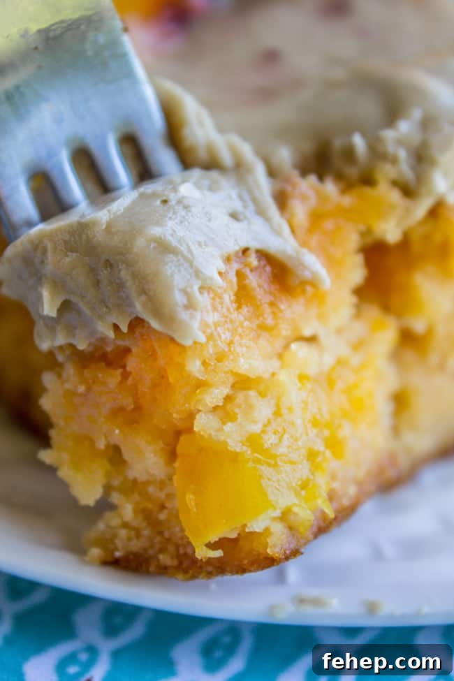 a slice of peach cake with brown sugar frosting with a fork in it.
