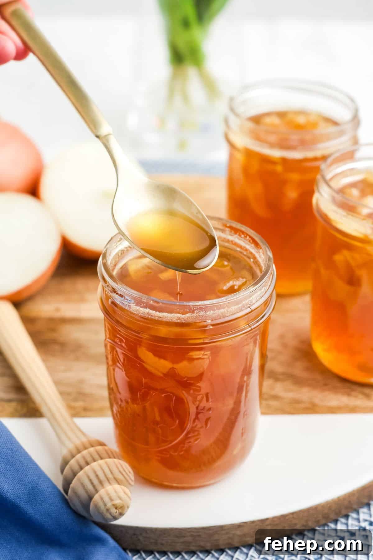 Homemade Honey and Onion Cough Syrup Recipe for Quick Relief 9 A spoonful of honey onion syrup held up over a jar on the table.