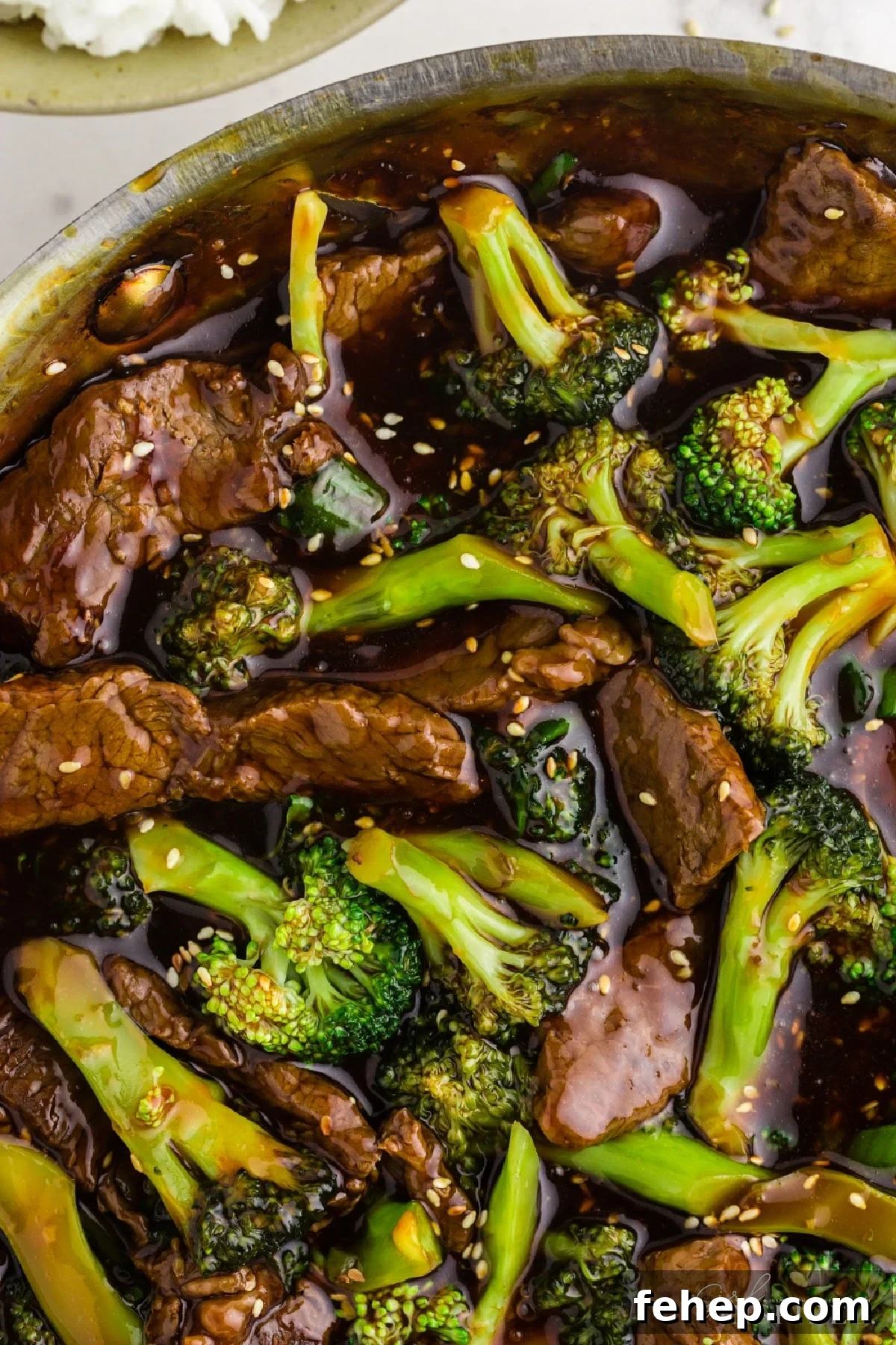 Panda Express Beef and Broccoli Recipe (Copycat Version) 13 Closeup of strips of beef and broccoli florets in thick sauce with sesame seeds.
