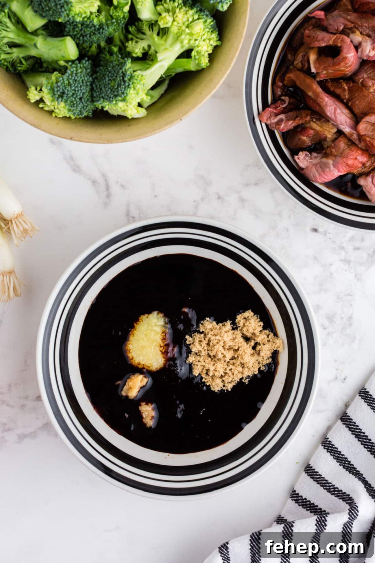 Panda Express Beef and Broccoli Recipe (Copycat Version) 5 Soy sauce, brown sugar, garlic paste, ginger paste, in bowl alongside bowl of marinating meat and bowl of broccoli.