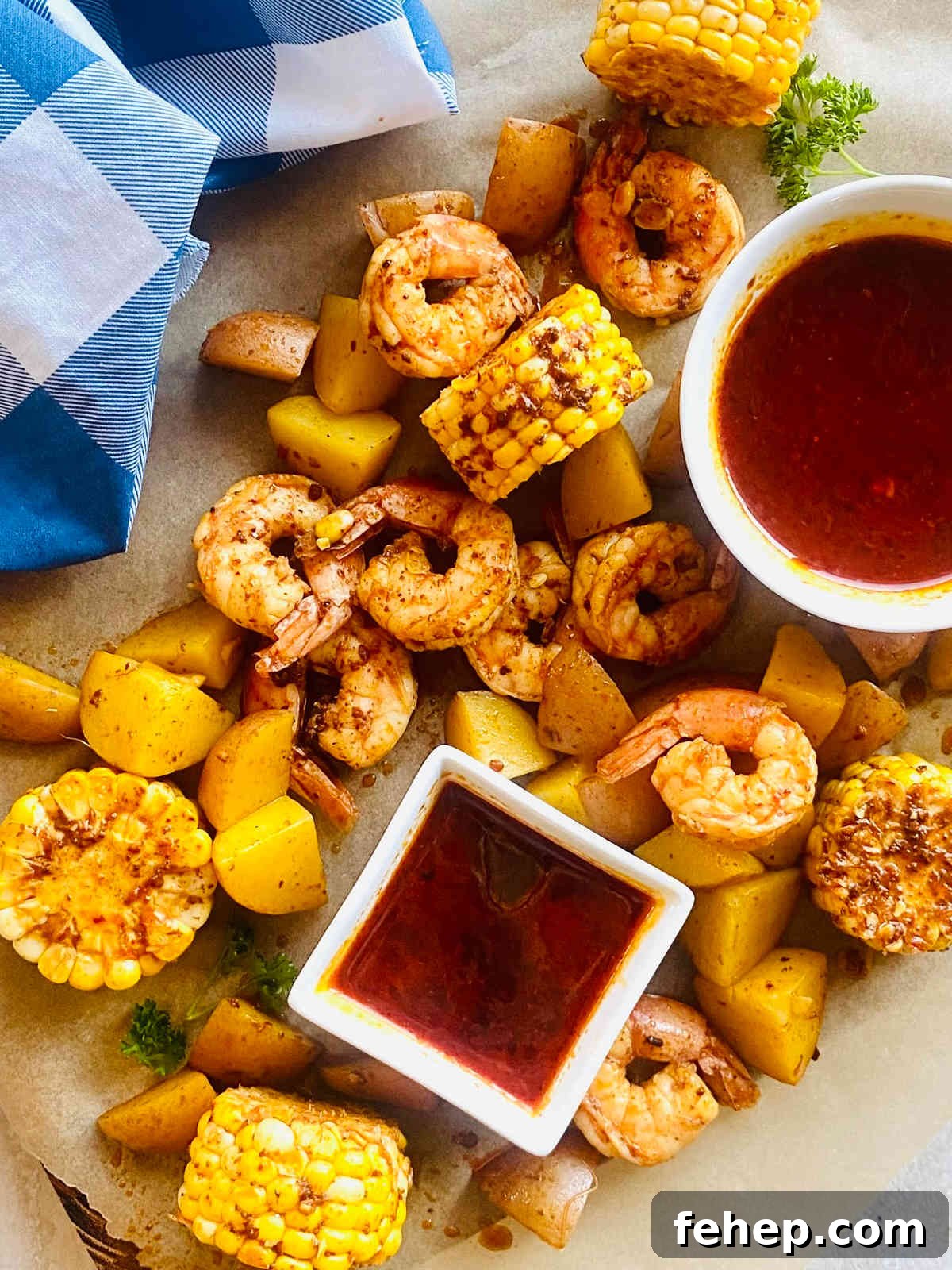 seafood sauce in a dish surrounded by shrimp, corn and potatoes in the seafood boil sauce.