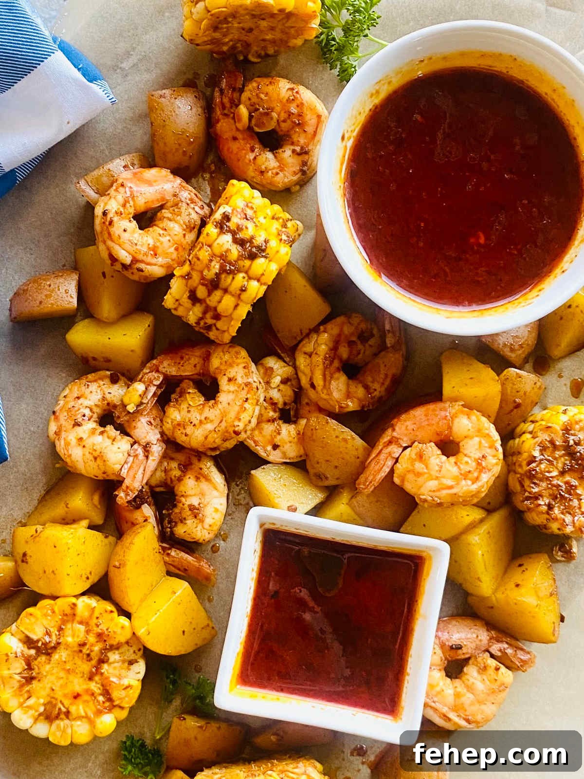 seafood boil sauce in a dish surrounded by shrimp, corn and potatoes in the seafood boil sauce.