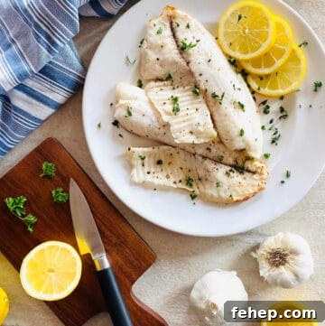 air fryer tilapia on a plate with lemon and parsley