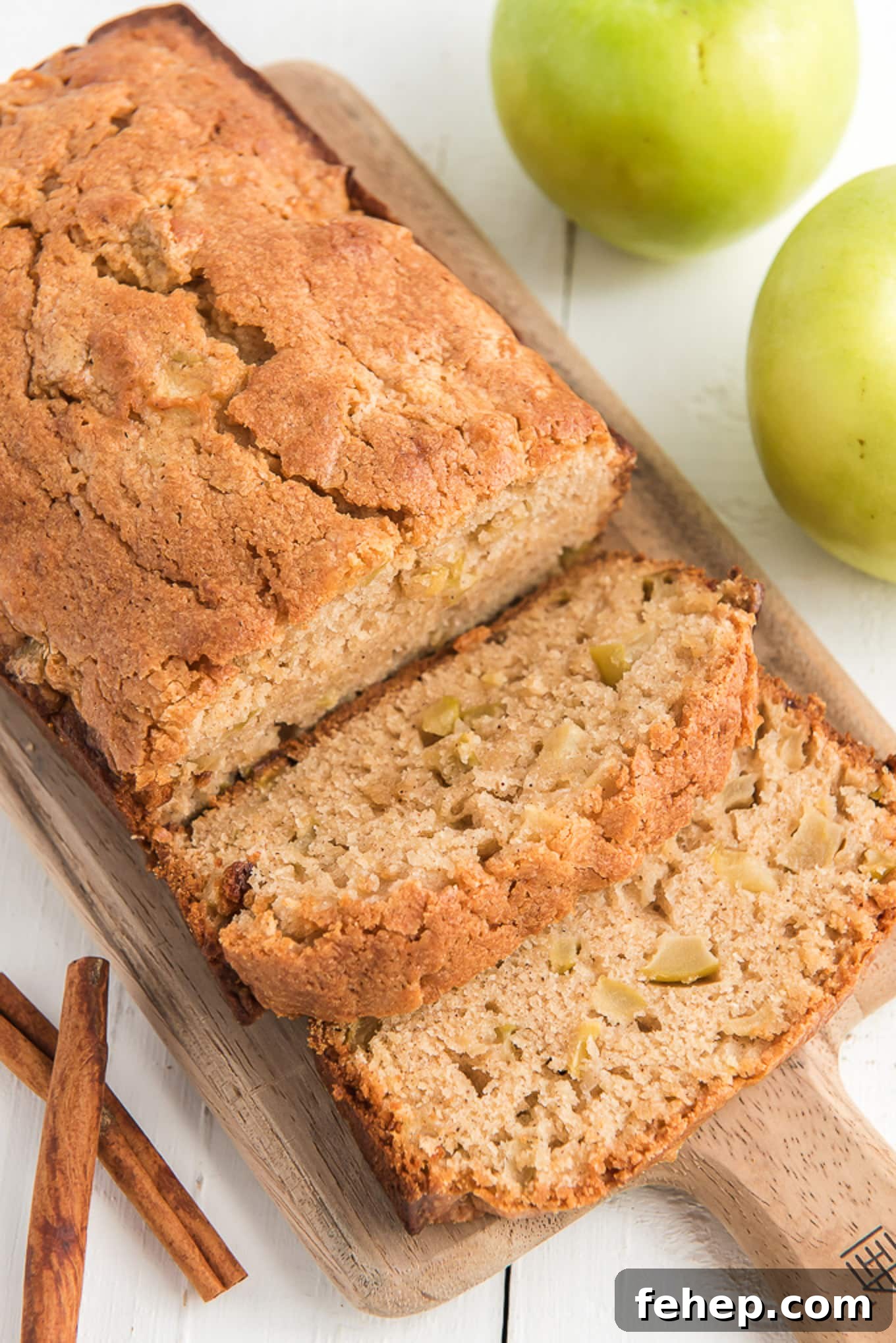 Moist Homemade Apple Bread Recipe with Cinnamon Sugar Swirl 2 An overhead of apple bread on a cutting board with whole apples next to it and a few slices cut.