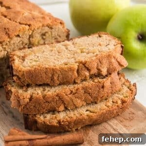 Moist Homemade Apple Bread Recipe with Cinnamon Sugar Swirl 7 A loaf apple bread with three slices stacked in front of the loaf on a cutting board.