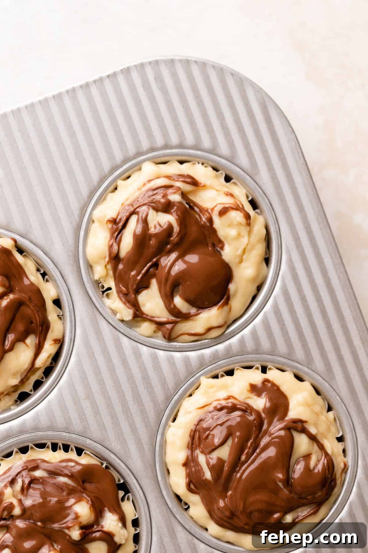 Nutella swirled on the tops of the muffin batter.