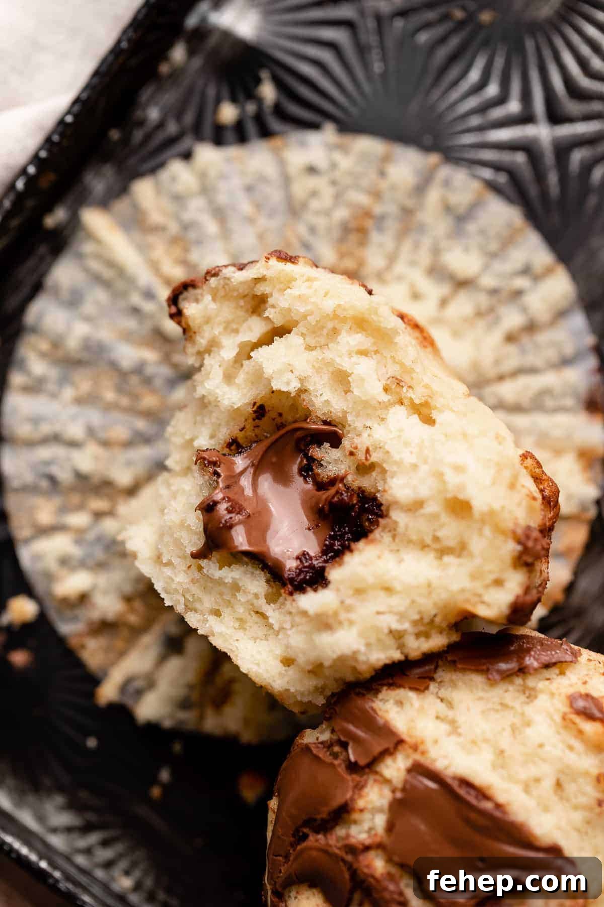 a nutella muffin cut in half to show the gooey chocolate hazelnut spread in the center.