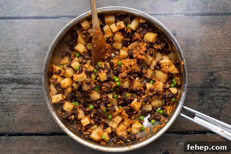 Vegan Empanadas: Flavorful Plant-Based Empanada Recipes 10 Large skillet with empanada filling ingredients on a wooden background.