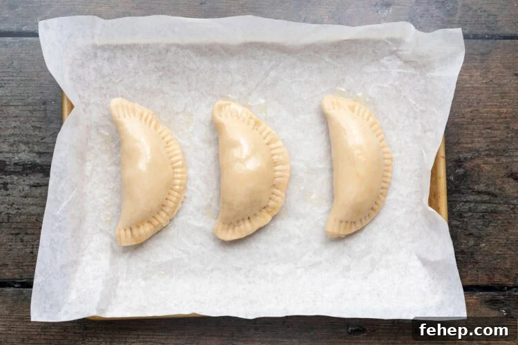 Vegan Empanadas: Flavorful Plant-Based Empanada Recipes 11 Overhead view of 3 vegan empanadas on a baking sheet lined with parchment paper.