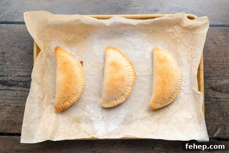 Vegan Empanadas: Flavorful Plant-Based Empanada Recipes 12 Overhead view of baked empanadas on a baking sheet lined with parchment paper.