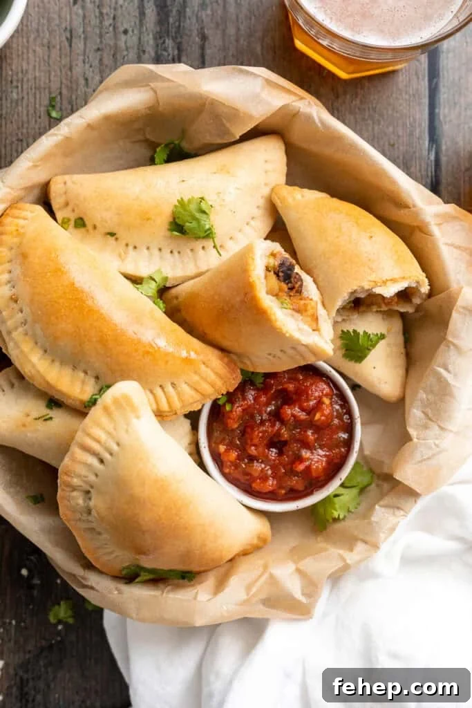 Vegan Empanadas: Flavorful Plant-Based Empanada Recipes 3 Overhead view of a bowl of vegan empanadas next to a small ramekin of red salsa.
