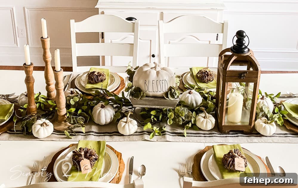 centerpiece of dining table with 3 candle sticks on left side wood bowl with Rae Dunn pumpkin in middle and wood candle lanter on right side