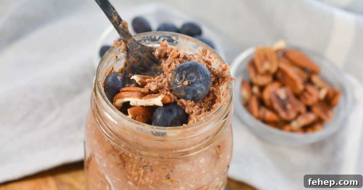 A jar of Tiramisu Overnight Oats topped with fresh blueberries and pecans, with a fork inside. A small bowl of pecans and blueberries is in the background.