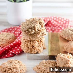 A stack of No Bake Peanut Butter Oatmeal Cookies sits on a marble and wood board, with more cookies and a red polka dot cloth nearby.