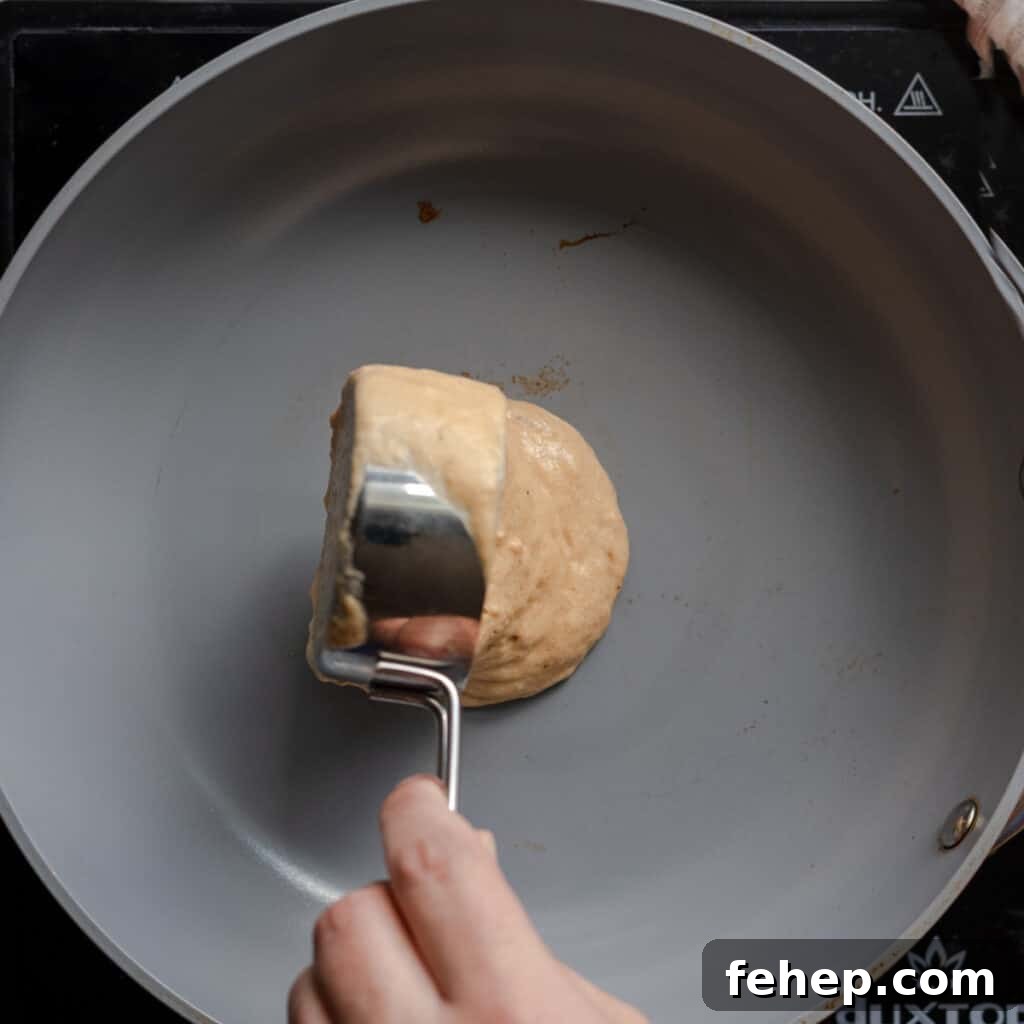 woman's hands pouring pancake batter into skillet