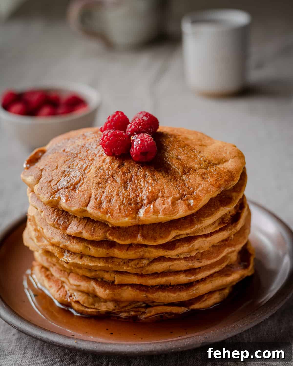 a stack of vegan pumpkin pancakes with raspberries on top