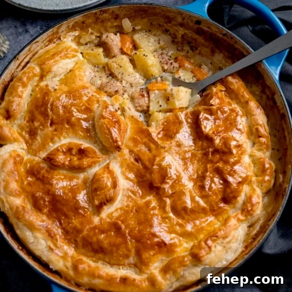 Square image of a sausage and mustard pie - shot from overhead. There is a spoonful of the pie filling being taken out.