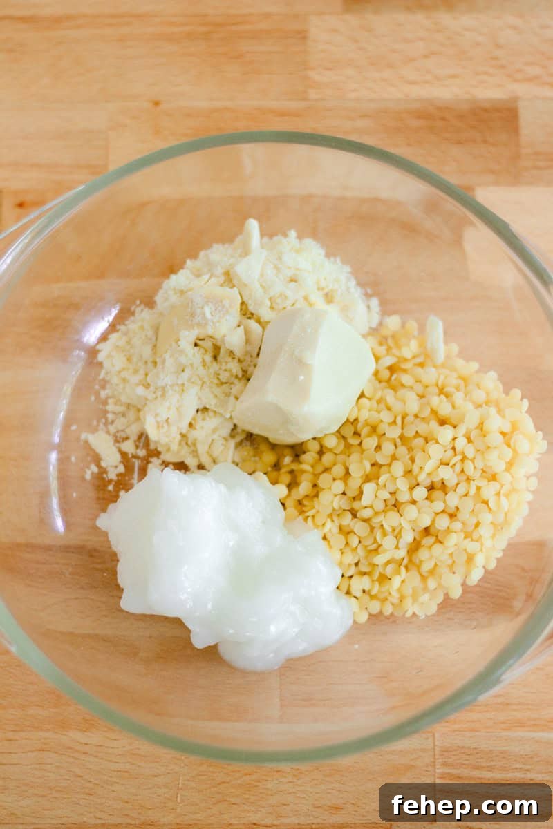 A glass bowl with lotion bar ingredients sitting on a wooden table.