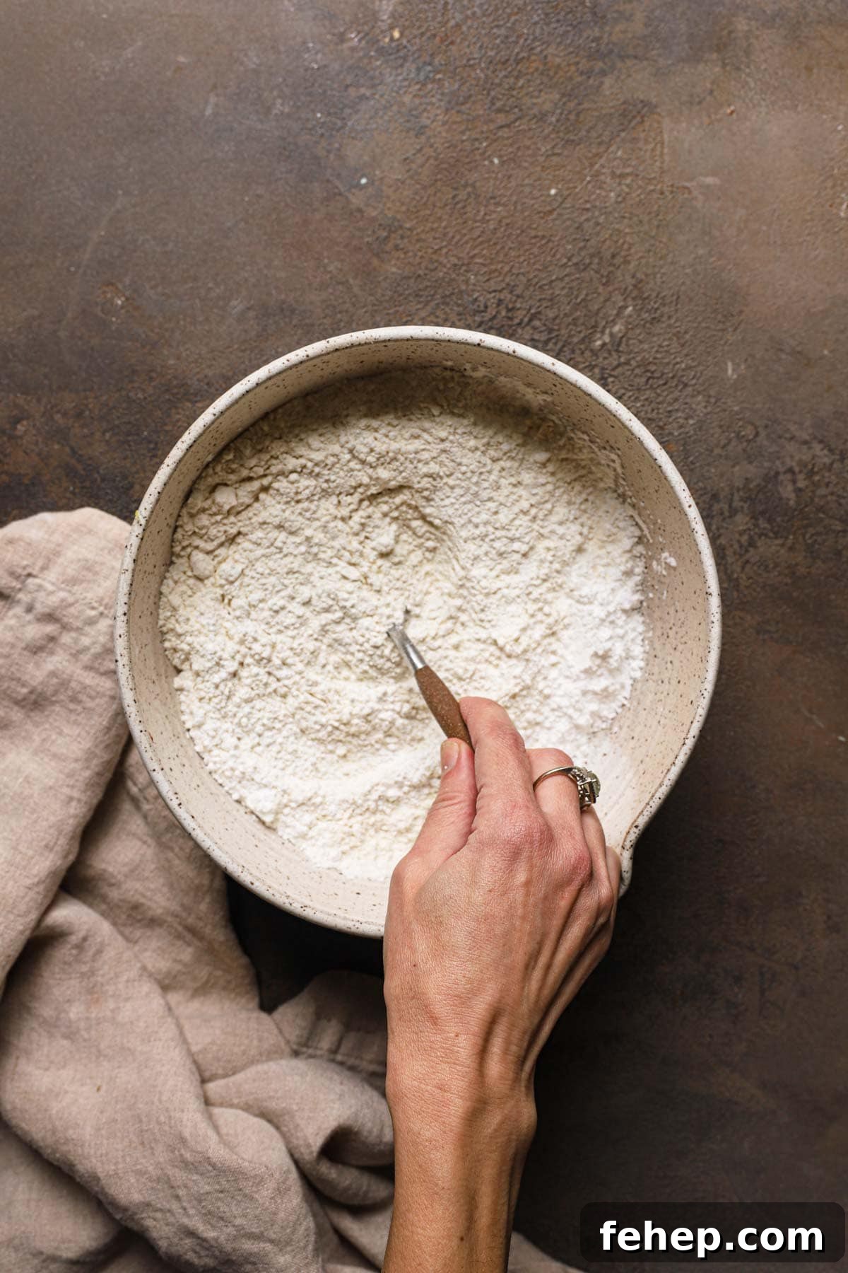Italian Pasta Frolla Shortcrust Pastry: Multipurpose Dough Guide 7 A hand mixing flour in a large bowl.