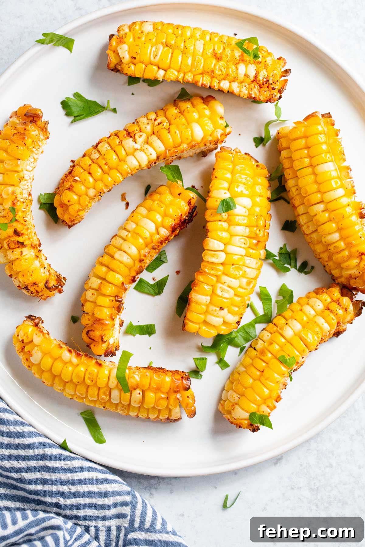 Crispy Air Fryer Corn Ribs Recipe for Summer BBQs 2 Corn ribs on a white plate with parsley.