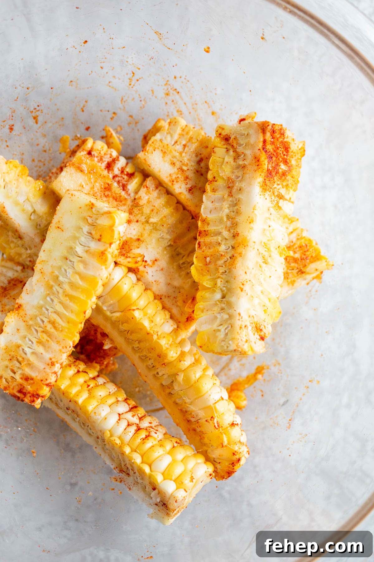 Crispy Air Fryer Corn Ribs Recipe for Summer BBQs 6 Corn ribs with seasonings in a large bowl.